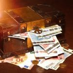 Vintage wooden treasure chest overflowing with euro banknotes and gold coins, symbolizing wealth, investment, and financial success.